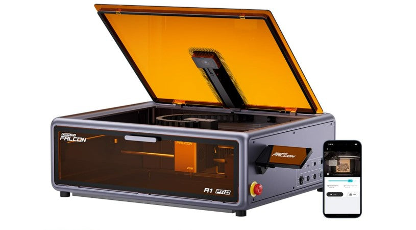 Creality Falcon A1 Pro laser engraver with lid open and camera visible, beside a smartphone showing the monitoring app